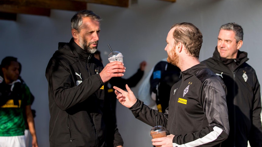 Marco Rose von Borussia Mönchengladbach bekommt nach dem Training von Melf Carstensen einen Shake gereicht.