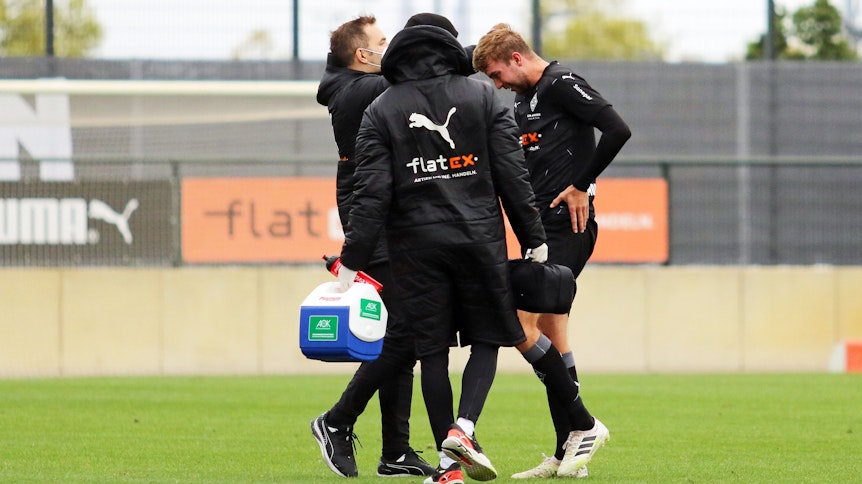 Christoph Kramer, Mittelfeldspieler der Gladbacher Borussia, wird von zwei Medizinern am Spielfeldrand behandelt.