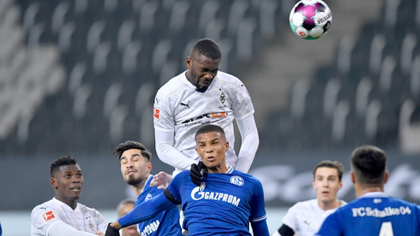 Marcus Thuram (oben), Stürmer der Gladbacher Borussia, setzt sich gegen Schalkes Malick Thiaw (M.) durch