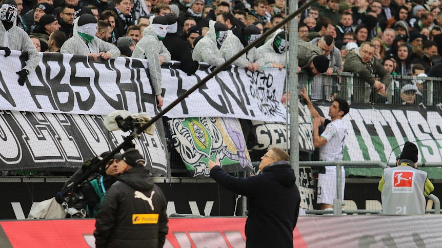 Manager Max Eberl, Kapitän Lars Stindl und das Gladbacher Publikum verhindern mit ihrem Eingreifen, dass vermummte Chaoten einen Spielabbruch provozieren.