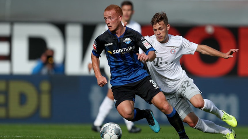 Sebastian Vasiliadis (l.), Mittelfeldspieler des SC Paderborn, im Kampf um den Ball mit Joshua Kimmich (r.) vom FC Bayern München.