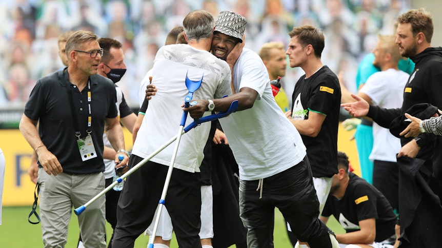 Marcus Thuram (M.) wird von Marco Rose nach dem feststehenden Champions-League-Einzug nach dem Spiel gegen Hertha BSC umarmt.