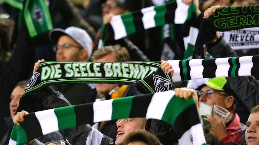 Gladbach-Fans halten ihre Schals hoch.