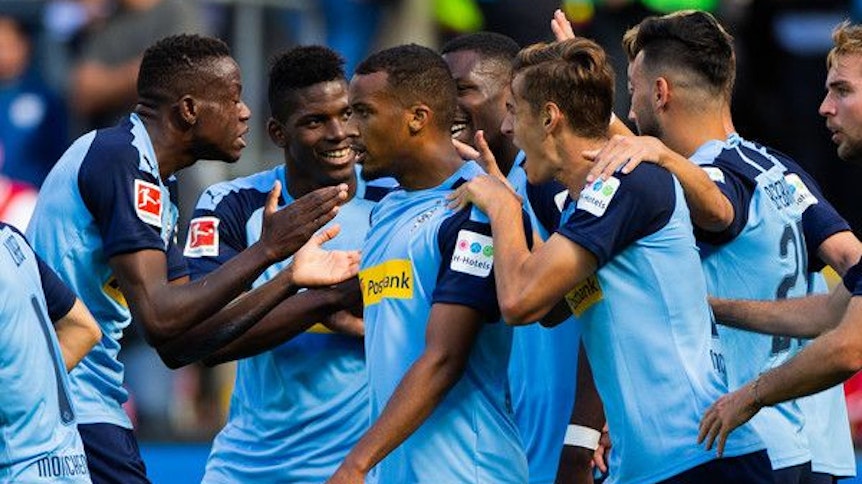 Der Gladbacher Spieler Alassane Plea wird nach einem Torerfolg von seinen Mitspielern umringt.