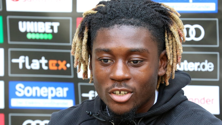 Gladbachs Neuzugang Manu Koné stellt sich in einer Medienrunde im Trainingslager in Harsewinkel-Marienfeld den Fragen der anwesenden Journalisten. Er schaut dabei nachdenklich.