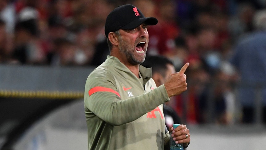 Jürgen Klopp, Trainer des englischen Top-Klubs FC Liverpool, brüllt bei einem Testspiel gegen Hertha BSC in Innsbruck am 29. Juli 2021 Anweisungen auf das Spielfeld. Mit dem rechten Arm gestikuliert er, in der linken Hand hält er derweil eine Getränkeflasche.