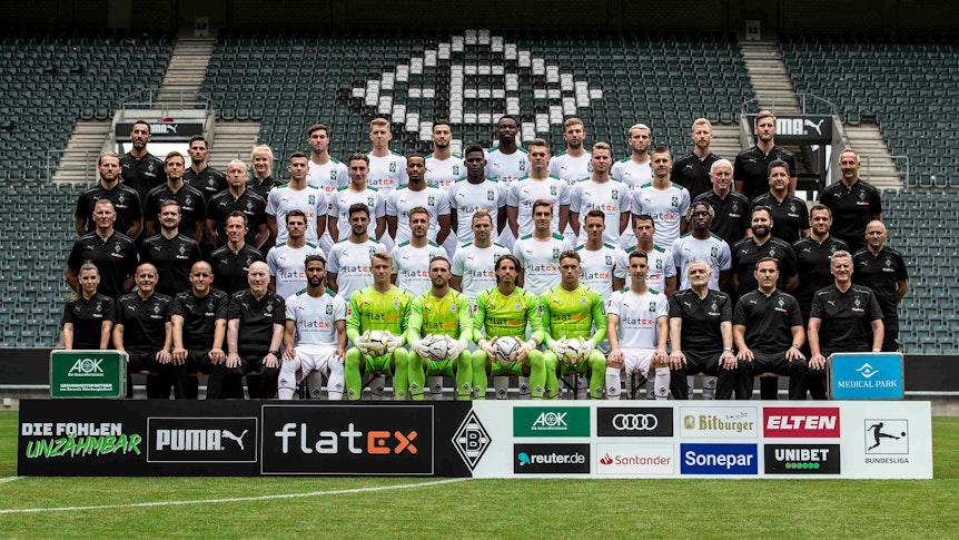 Fußball-Bundesligist Borussia Mönchengladbach hat am Sonntag, 1. August 2021, die Fohlen-Elf zum neuen Mannschafts-Foto zusammenkommen lassen. Insgesamt 51 Personen sind darauf zu sehen. Die Aufnahme ist im Borussia-Borussia-Park gemacht worden. Die Spieler tragen weiße Trikots, die Torhüter neongelbe. Das Betreuer- und Trainer-Team trägt hingegen schwarze Trainingsmonturen des Ausrüsters Puma.