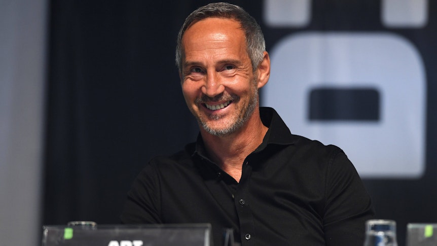 Adi Hütter sitzt auf einer Bühne im Borussia-Park. Gladbachs Trainer lächelt, er trägt ein schwarzes Hemd.