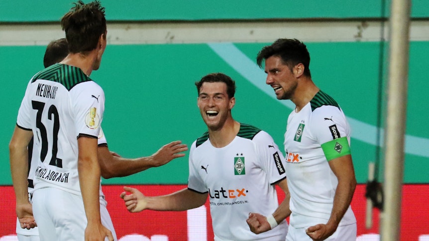 Die Gladbacher Florian Neuhaus und Joe Scally bejubeln gemeinsam mit Torschütze Lars Stindl das 1:0 in der 1. Runde des DFB-Pokals beim 1. FC Kaiserslautern am 9. August 2021.
