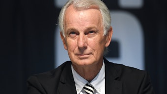 Gladbachs Vize-Präsident sitzt auf der Bühne im Borussia-Park und lächelt.