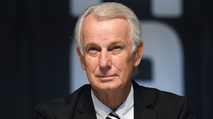 Gladbachs Vize-Präsident sitzt auf der Bühne im Borussia-Park und lächelt.
