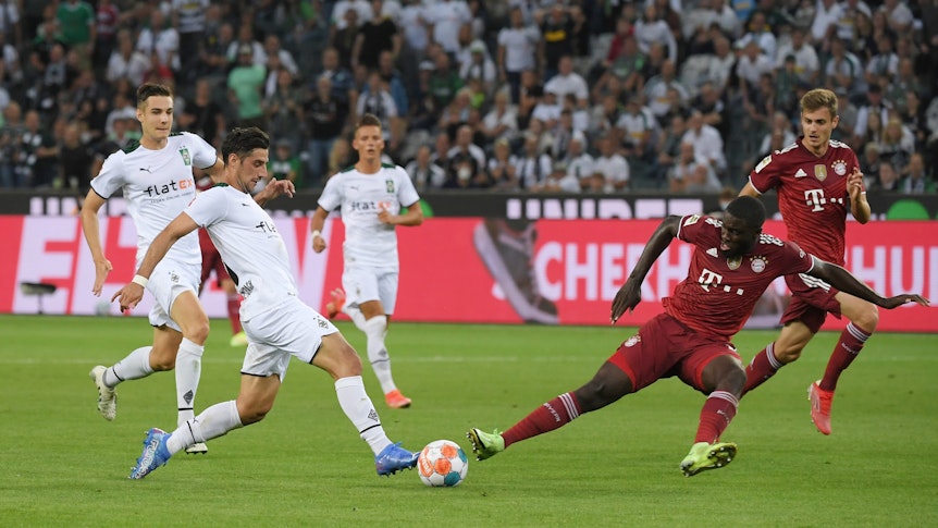 Gladbachs Lars Stindl (l.) beim Bundesliga-Eröffnungsspiel am 13. August 2021 im Zweikampf mit Bayerns Dayot Upamecano (r.).