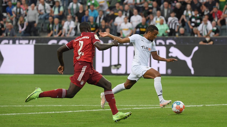 Gladbach-Stürmer Alassane Plea (r.) beim Abschluss, Bayern-Verteidiger Dayot Upamecano (l.) versucht den Borussen noch zu stoppen, der trifft aber für die Fohlen.