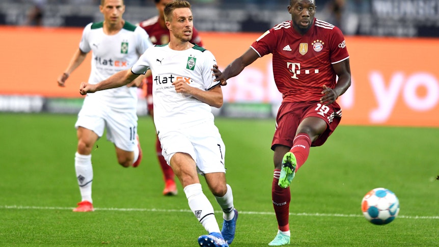 Gladbachs Patrick Herrmann (l.) am 13. August 2021 im Zweikampf mit Bayerns Alphonso Davies (r.) beim Bundesliga-Auftakt-Match im Borussia-Park.