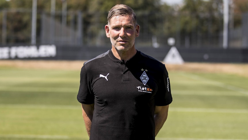 Gladbach-Legende und Torwarttrainer Uwe Kamps blickt in die Kamera, seine Arme hat er auf dem Rücken verschränkt.
