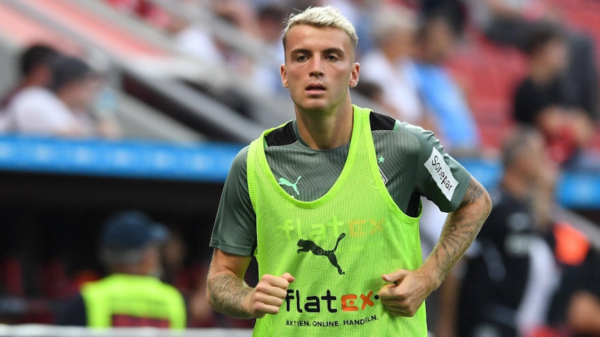 Gladbach-Verteidiger Jordan Beyer, hier zu sehen am 21. August 2021 bei Borussias Niederlage (0:4) in Leverkusen. Beyer läuft sich an der Seitenlinie warm, er trägt ein gelbes Leibchen.