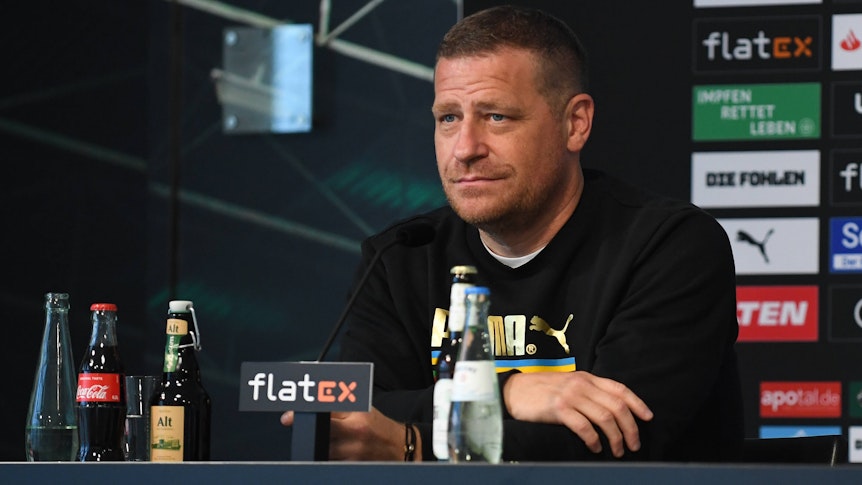 Gladbachs Sportdirektor Max Eberl lächelt mild auf der Pressekonferenz vor dem Auswärtsspiel zwischen Borussia Mönchengladbach und Union Berlin am 27. August 2021 im Borussia-Park am Podest sitzend.