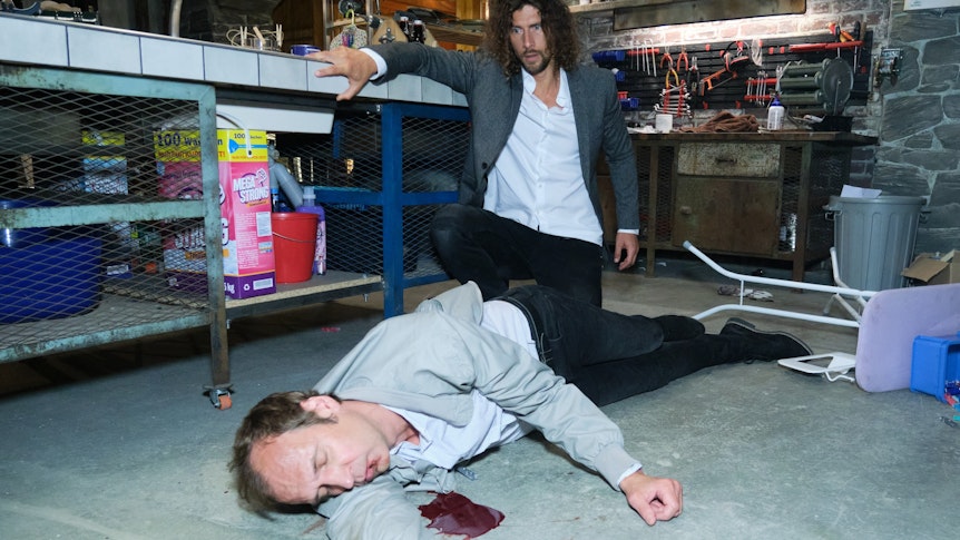 Torsten Knippertz liegt in seiner RTL-Rolle als Marius Popovic blutend und leblos auf dem Keller-Boden. Im Hintergrund ist Schauspieler Jakob Graf zu sehen, der bei „Unter uns“ den Luke Färber spielt.