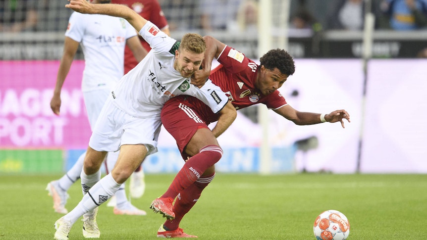 Gladbach-Profi Christoph Kramer (l.) im Zweikampf mit Bayern-München-Spieler Serge Gnabry (r.) beim Bundesliga-Duell am 13. August 2021 im Borussia-Park. Kramer und Gnabry ringen um den Ball.
