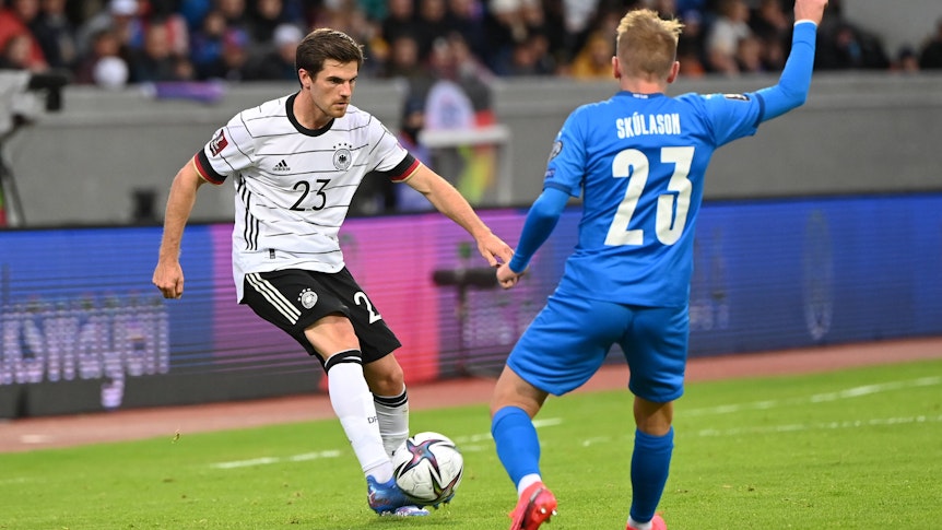 Gladbach-Profi Jonas Hofmann (l.). Auf diesem Foto ist das Fohlen im Trikot der DFB-Elf beim WM-Qualifikations-Duell am 8. September 2021 gegen Island in Reykjavik zu sehen. Hofmann spielt mit dem rechten Fuß den Ball, sein Gegenspieler hebt den rechten Arm.