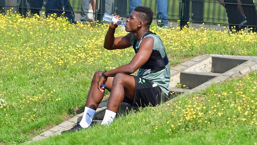 Gladbach-Stürmer Breel Embolo während einer Trinkpause bei einer Trainingseinheit der Fohlen am 4. August 2021 im Borussia-Park. Embolo sitzt auf einer Treppe am Spielfeldrand und nimmt einen Schluck aus einer Wasserflasche.