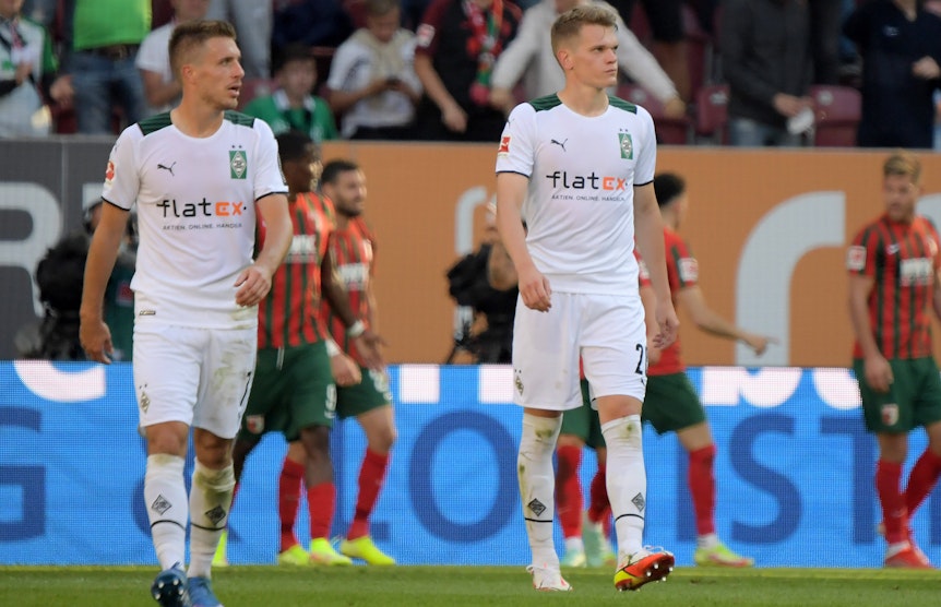 Matthias Ginter (r.) und Patrick Herrmann (l.) im Trikot von Borussia Mönchengladbach am 18. September 2021 beim Bundesliga-Spiel in Augsburg. Beide schauen zur Seite.