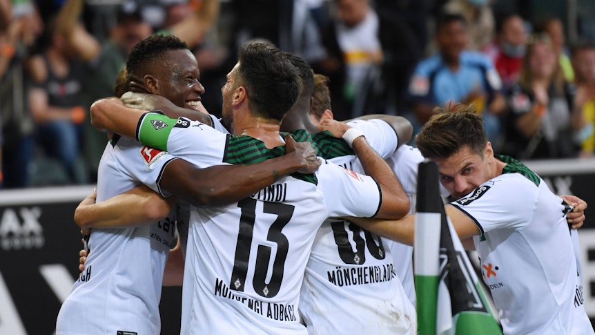 Denis Zakaria und Lars Stindl (v.l.) liegen sich im Arm und bilden mit anderen Spielern von Borussia Mönchengladbach eine Jubeltraube am 25. September 2021.