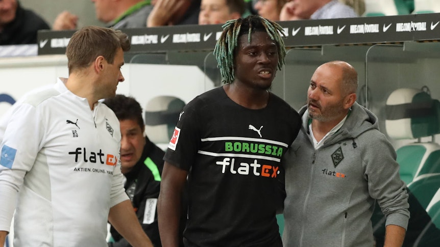 Manu Koné von Borussia Mönchengladbach, hier mit Co-Trainer Oliver Neuville (r.) musste in der 60. Spielminute verletzt ausgewechselt werden.