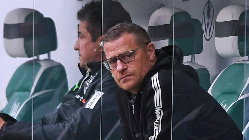 Gladbach-Manager Max Eberl, hier zu sehen am 2. Oktober 2021 beim Bundesliga-Duell seiner Borussia in Wolfsburg, hat in den kommenden Wochen und Monaten alle Hände voll zu tun. Eberl sitzt auf der Gästebank und blickt in die Kamera.