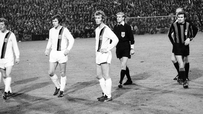 Die Gladbach-Spieler Herbert Wimmer, Jupp Heynckes und Rainer Bonhof (v.li.) verharren auf dem Rasen des Bökelbergstadions. Zuvor hatte eine Cola-Dose den Spieler Roberto Boninsegna von Inter Mailand beim Europapokal-Duell am 20. Oktober 1971 getroffen. Das Spiel endete 7:1 für Gladbach, wurde aber später von der UEFA annulliert.