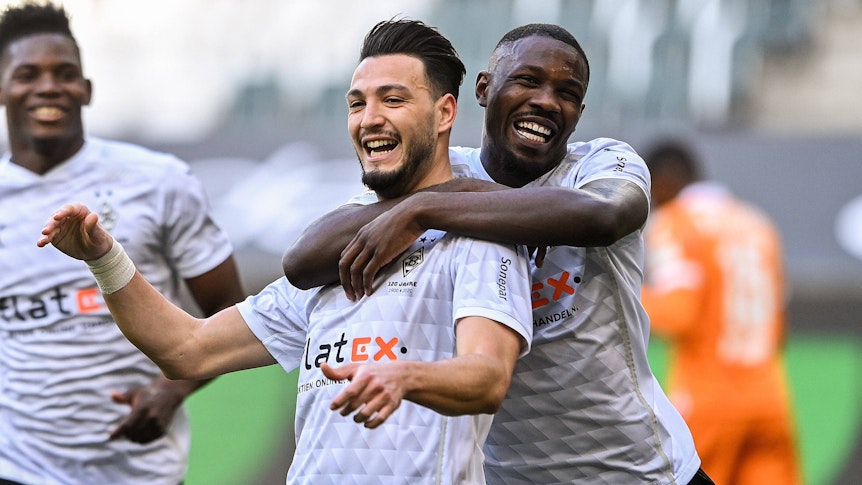 Auf Verteidiger Ramy Bensebaini (Mitte) und Stürmer Marcus Thuram muss Borussia Mönchengladbach bereits seit Wochen verzichten. Auf diesem Foto sind die beidem 25. April 2021 im Borussia-Park zu sehen. Thuram umarmt Bensebaini.