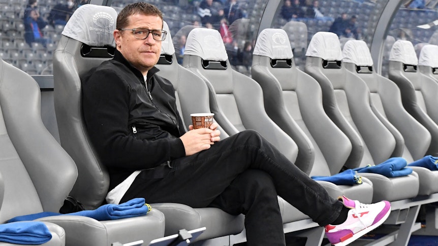 Max Eberl, Manager von Fußball-Bundesligist Borussia Mönchengladbach, sitzt vor dem Topspiel bei Hertha BSC am Samstag (23. Oktober 2021) noch ruhig auf der Ersatzbank im Olympiastadion. Eberl hält einen Getränkebecher in den Händen.