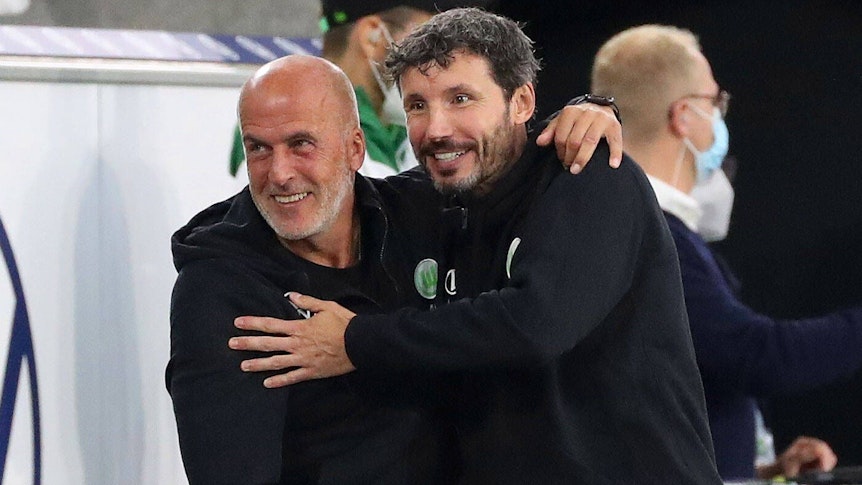 Mark van Bommel (r.) ist am Sonntag (24. Oktober 2021) als Cheftrainer bei Bundesligist VfL Wolfsburg entlassen worden. Muss nun auch sein Assistent Michael Frontzeck, ehemaliger Gladbach-Coach, um seinen Job bangen? Frontzeck und van Bommel umarmen sich. Dieses Foto stammt vom 29. August 2021.