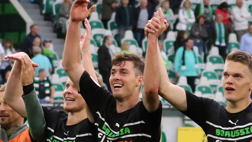 Joe Scally (Mitte) von Borussia Mönchengladbach, mit seinen Teamkollegen Nico Elvedi (l.) und Matthias Ginter (r.) beim Feiern mit den Fans nach der Partie beim VfL Wolfsburg am 2. Oktober 2021.