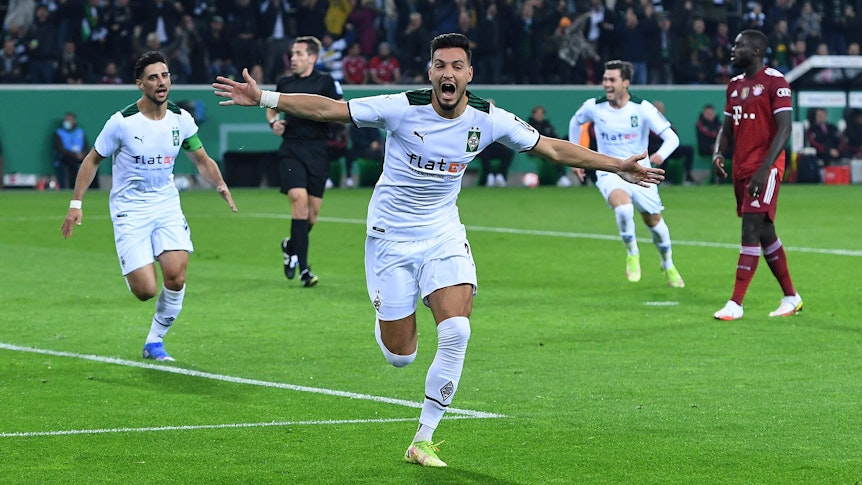 Ramy Bensebaini (M.) jubelt über einenTreffer für Borussia Mönchengladbach im DFB-Pokal-Spiel gegen Bayern München am 27. Oktober 2021 im Borussia-Park. Im Hintergrund jubeln auch Stindl und Scally.