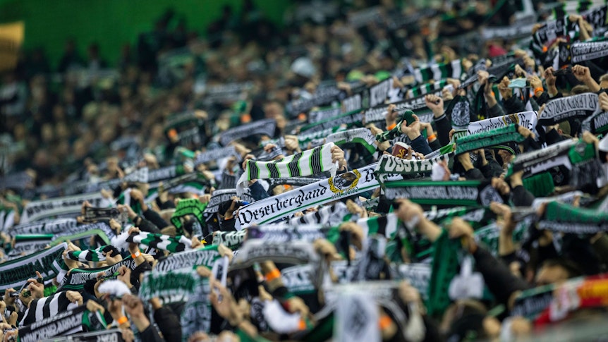 Fans von Fußball-Bundesligist Borussia Mönchengladbach am 20. November 2021 in der Nordkurve im Borussia-Park. Sie halten ihre Schals in die Höhe.