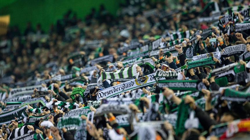 Fans von Fußball-Bundesligist Borussia Mönchengladbach am 20. November 2021 im Borussia-Park. Sie halten ihre Schals hoch.