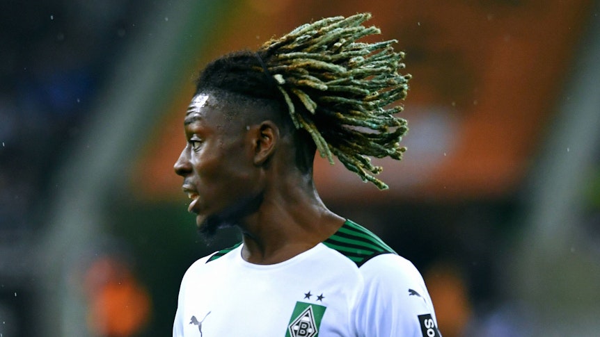 Manu Koné fällt mit starken Leistungen und einer schrillen Frisur in der Fußball-Bundesliga auf. Der Mittelfeldspieler steht bei Borussia Mönchengladbach bis 2025 unter Vertrag. Auf diesem Foto ist er am 31. Oktober 2021 im Borussia-Park zu sehen. Koné blickt zur Seite.
