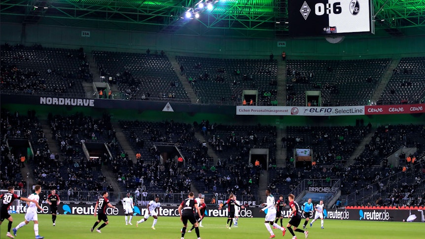 Borussia Mönchengladbach hat eine historische Niederlage am 6. Dezember 2021 erlebt. Gegen den SC Freiburg setzte es eine 0:6-Pleite. So hoch hatten die Fohlen zuvor noch nie im Borussia-Park verloren. Auf dem Platz sind Spieler beider Mannschaften zu sehen, derweil zeigt die Videowand das Ergebnis an.