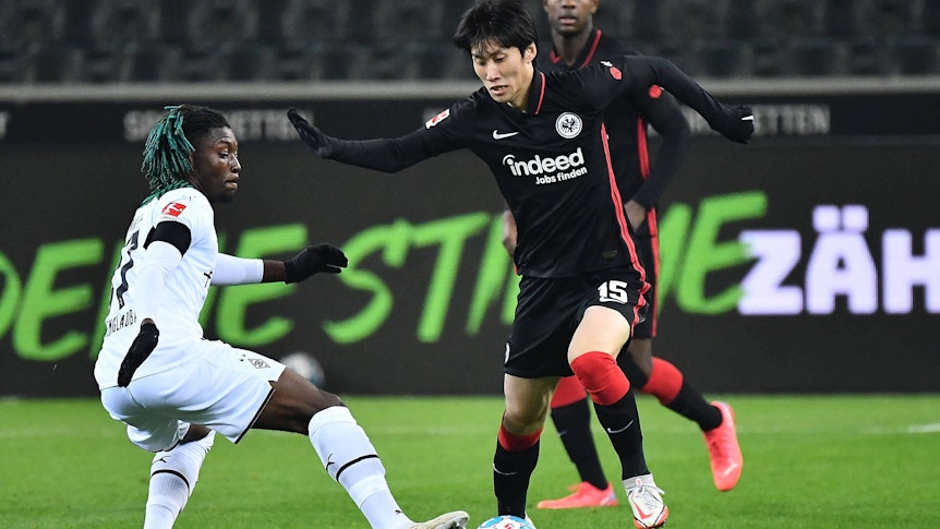 Manu Kone (l.) von Borussia Mönchengladbach versucht gegen Daichi Kamada (r.) von Eintracht Frankfurt an den Ball zu kommen, am 15. Dezember 2021.