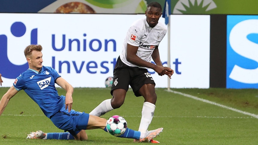 Stefan Posch (l.) von der TSG Hoffenheim klärt einen Ball von Marcus Thuram (r.), Borussia Mönchengladbach, am 21. April 2021 im Bundesligaduell der beiden Teams.