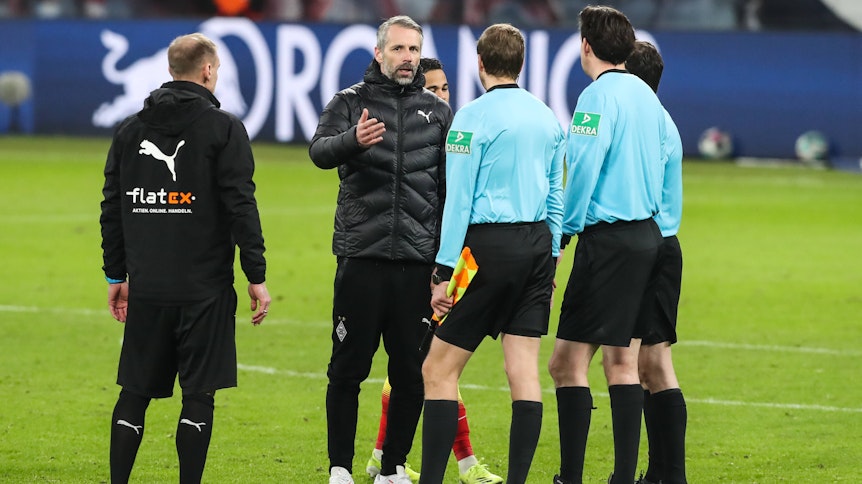 Gladbach-Trainer Marco Rose (M.) diskutiert mit Schiedsrichter Manuel Gräfe nach dem verlorenen Bundesliga-Topspiel (27. Februar 2021) bei RB Leipzig. Rose gestikuliert und spricht. Sein Assistent Alexander Zickler (l.) schaut zu.