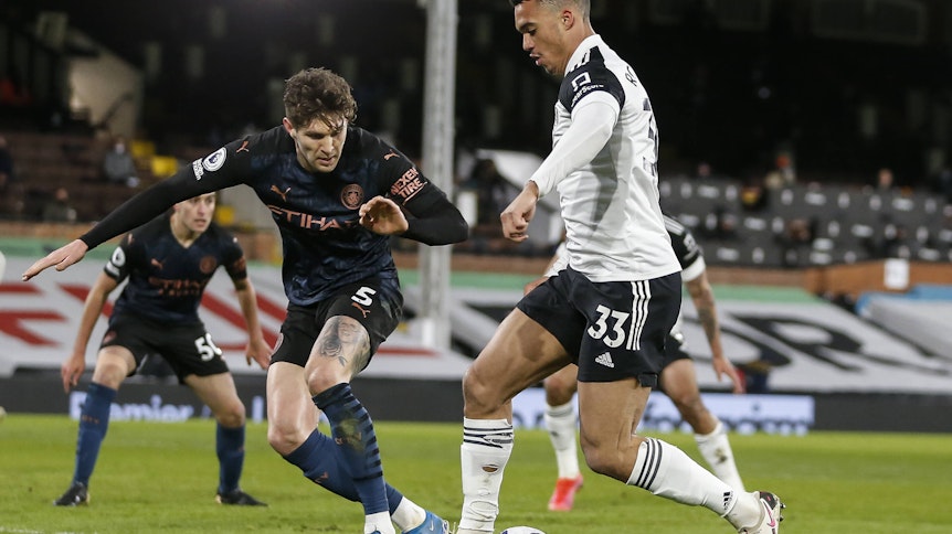 Fulhams Antonee Robinson (r) im Duell mit Manchester Citys John Stones während des Premier-League-matchs zwischen Fulham and Manchester City am 13. März 2021.