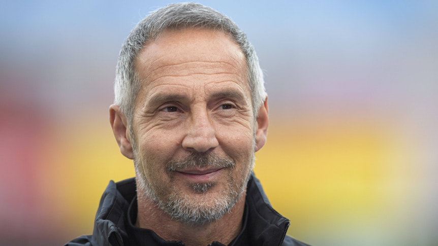 Trainer Adi Hütter macht ein freundliches Gesicht und lächelt in die Kamera.