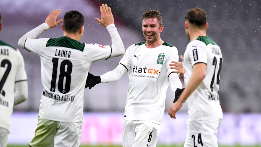Christoph Kramer (M.) bejubelt mit Stefan Lainer (l.) und Tony Jantschke (r.) den 2:1-Siegtreffer von Borussia Mönchengladbach zum Bundesliga-Rückrundenauftakt (7. Januar 2021) bei Bayern München. Kramer lacht und breitet die Arme aus.