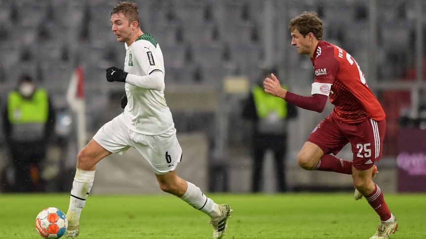 Borussias Mittelfeldspieler Christoph Kramer (l.), Weltmeister von 2014, im Duell mit Weltmeister und Bayern-München-Star Thomas Müller am 7. Januar 2022 in der Allianz-Arena. Kramer läuft mit dem Ball und wird von Müller gejagt.