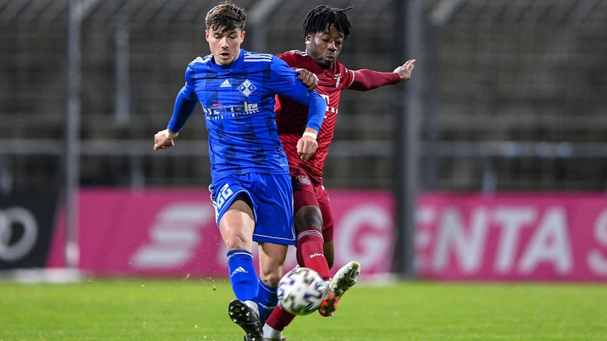 Semir Telalovic (l.) von FV Illertissen, hier am 3. Dezember 2021 in der Regionalliga Bayern im Duell mit Bright Akwo Arrey-Mbi (r.) von Bayern München II, steht vor einem Wechsel zu Borussia Mönchengladbach. Telalovic schießt den Ball nach vorne.