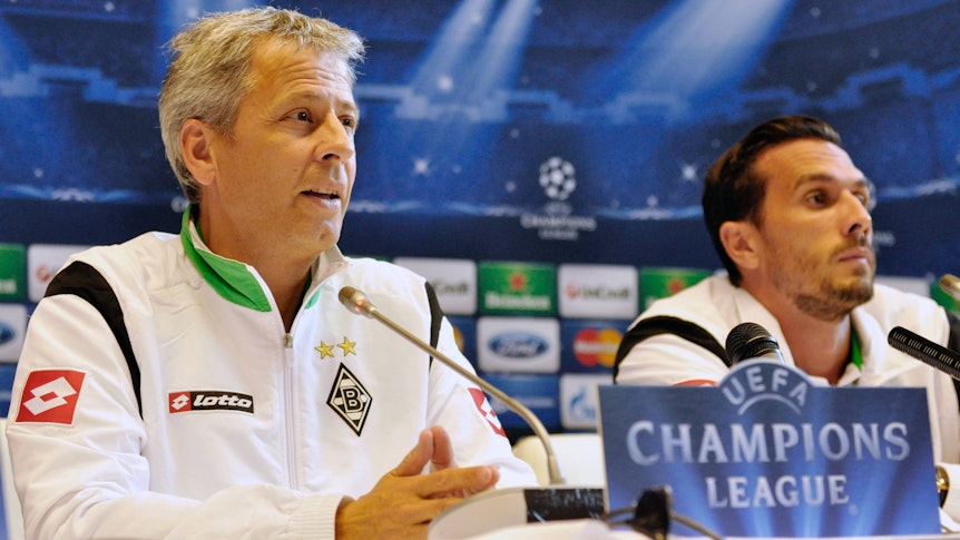 Ex-Gladbach-Kapitän Martin Stranzl (r.) und Ex-Borussia-Trainer Lucien Favre (l.) am 28. August 2012 bei einer Pressekonferenz vor dem Playoff-Duell zur UEFA Champions League gegen Dynamo Kiew in der Ukraine. Beide blicken in den Presseraum.