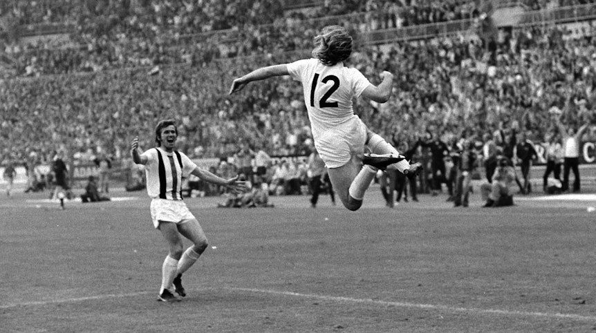 Günter Netzer (r.) springt nach seinem sensationellen Siegtreffer im DFB-Pokal-Finale am 23. Juni 1973 gegen den Erzrivalen 1. FC Köln seinem Borussia-Mönchengladbach-Team-Kollegen Jupp Heynckes (l.) im Düsseldorfer Rheinstadion in die Arme. Beide jubeln ausgelassen.