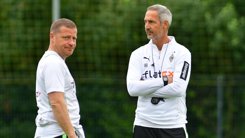 Ex-Sportdirektor Max Eberl (l.) und Gladbach-Trainer Adi Hütter (r.) unterhalten sich am 21. Juli 2021 im Trainingslager in Harsewinkel. Eberl schaut sichtlich genervt Richtung Fotografenkamera.